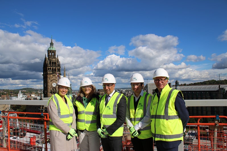 Dignitaries on a site visit atop a rooftop overlooking Sheffield