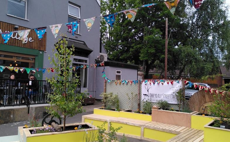 Business on Abbeydale Road, with bunting outside, benches and a few people sitting outside