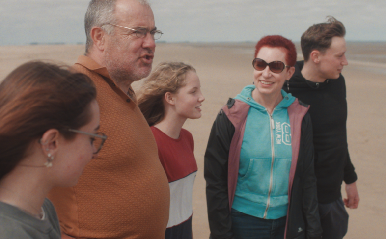 2 adults and 3 young people on a beach