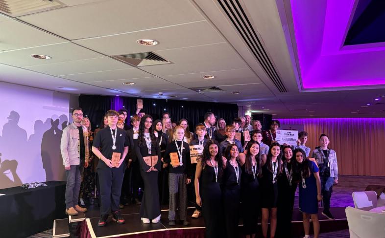 A group of young people standing on a stage with their awards