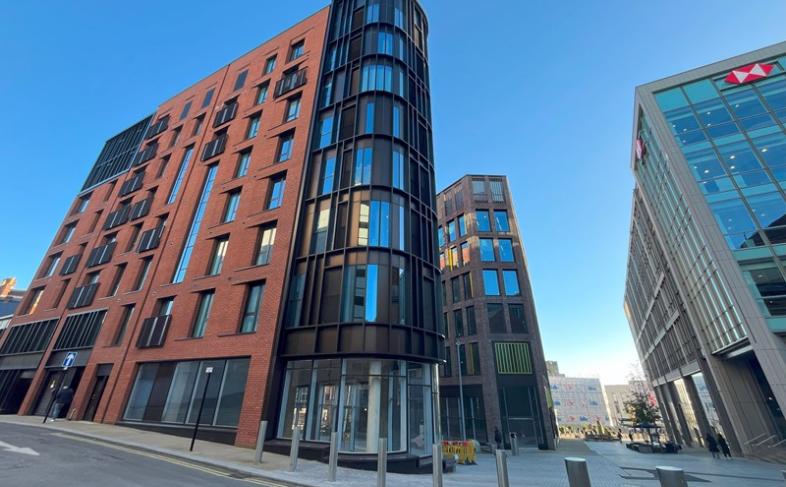 Image of a tall corner building known as the Burgess Building. The building is made of red brick with many glass windows