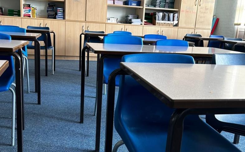 Classroom in a school, blue tables and chairs with cabinets in the background