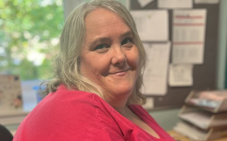 Janet, Head of Operations at Sheffield Women’s Aid, sitting at an office desk and smiling.