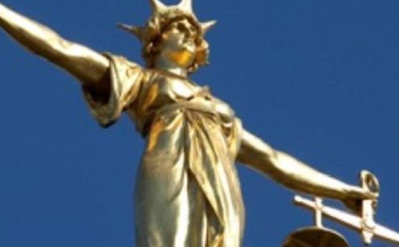 A golden statue of 'Lady Justice' holding a set of scales