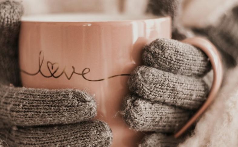 Image of gloved hands holding pink cup with the word 'love' on it.