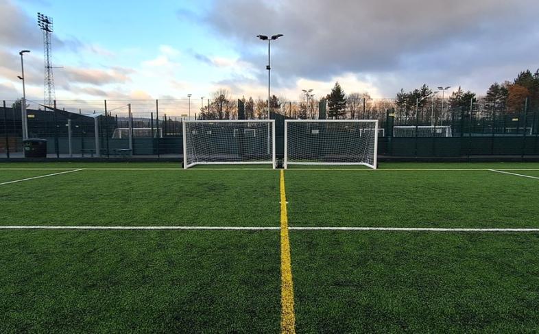 A football pitch with goal posts and nets under a cloudy evening sky