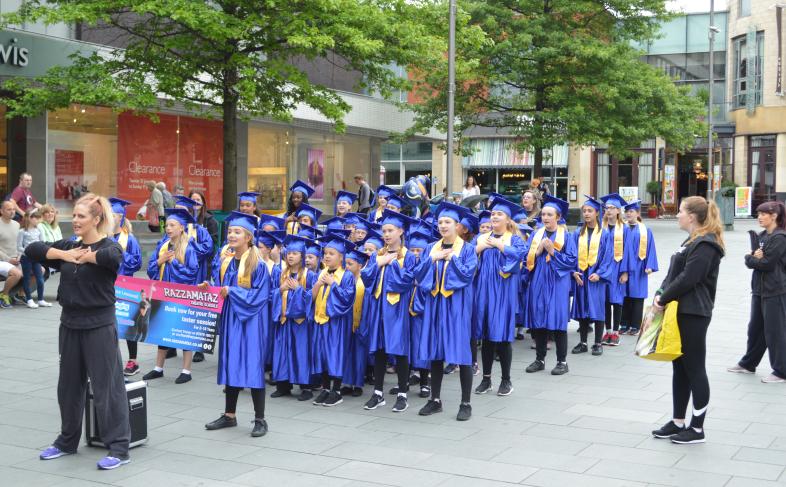 A Children's Universirty graduation ceremony sees children in gowns and mortar boards standing in line and waiting for the awards