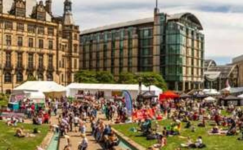 A packed Peace Gardens enjoying Sheffield Food Festival on a sunny day as people lay on the grass