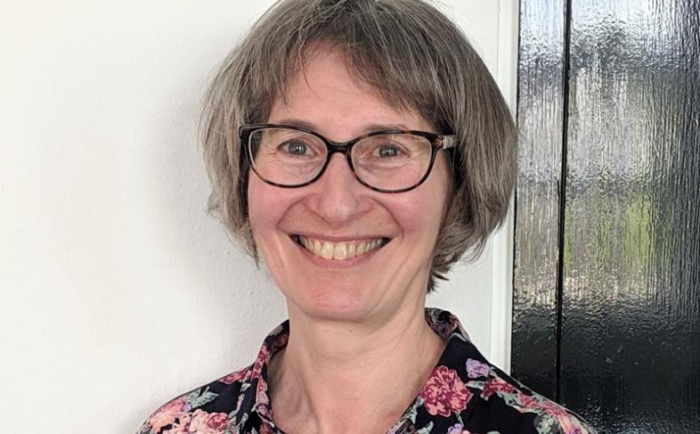 A head and shoulders shot of Mel Kanarek as Mel smiles into the camera while standing in front of a doorframe