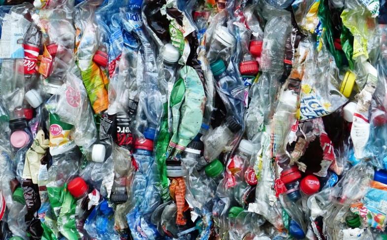 Plastic bottles crushed up and ready for recycling lie tightly packed together