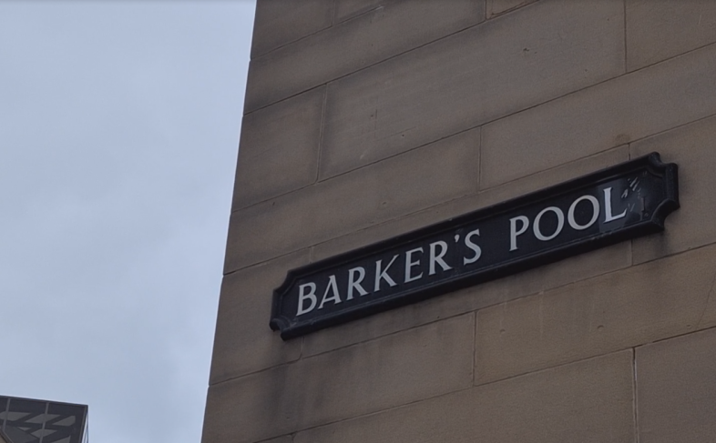 Sign saying Barker's Pool on a beige brick building with the grey sky in the background