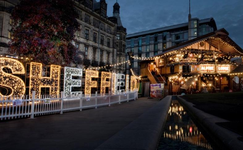 The word Sheffield is made up of giant letters covered in lights standing in front of the Town Hall with the Alpine bar building on the right hand side