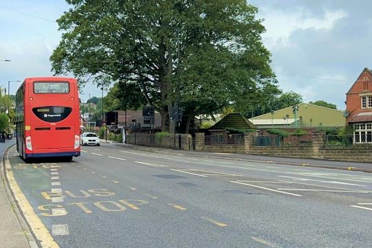 A double-decker bus passing by a bus stop in Sheffield.