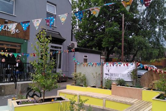 Business on Abbeydale Road, with bunting outside, benches and a few people sitting outside