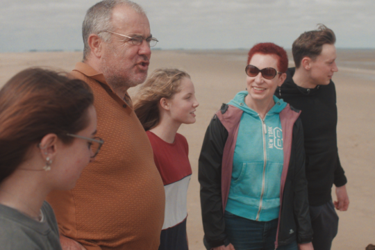 2 adults and 3 young people on a beach