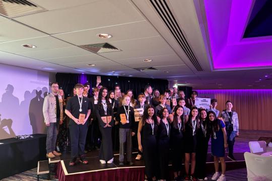 A group of young people standing on a stage with their awards