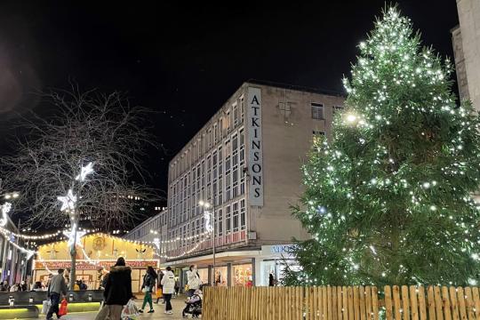 Image of The Moor at Christmas. There is a Christmas tree and Atkinson's store on the right. There are Christmas lights and people walking around