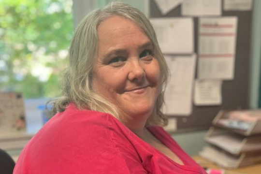 Janet, Head of Operations at Sheffield Women’s Aid, sitting at an office desk and smiling.