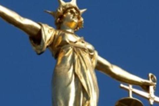 A golden statue of 'Lady Justice' holding a set of scales