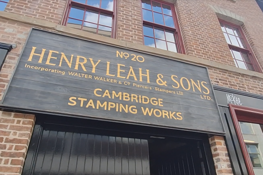 Image outside of Leah's Yard looking up at the new sign on the building