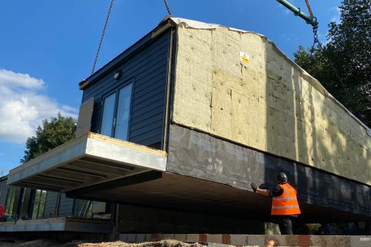 A net zero house being lowered by a crane