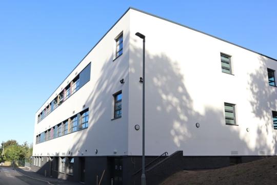 Image of Siverdale school building. It is white with windows all around it. The sky is blue above 