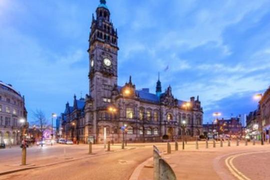 Image of the Town Hall at night on Pinstone Street with the lights shining in the windows on