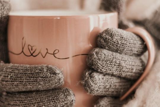 Image of gloved hands holding pink cup with the word 'love' on it.