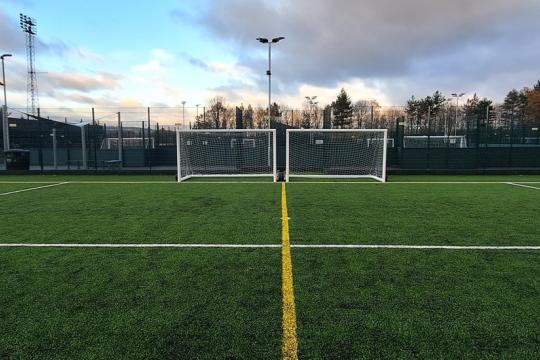 A football pitch with goal posts and nets under a cloudy evening sky