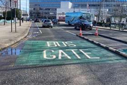 Painted words on Arundel Gate read 'bus gate', surrounded by green tarmac, to signal the point cars cannot pass or they receive a fine, as traffic drives past