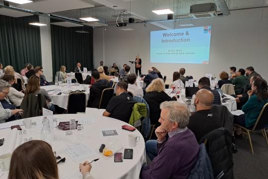 The room of attendees at the Rough Sleeping Summit listen to a speaker