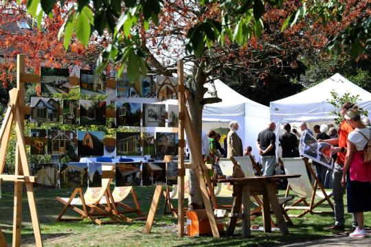 Visitors enjoying the different artwork displayed at Art in the Gardens, among a scenic background of trees. Photo: Ian Spooner