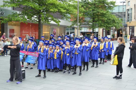 A Children's Universirty graduation ceremony sees children in gowns and mortar boards standing in line and waiting for the awards