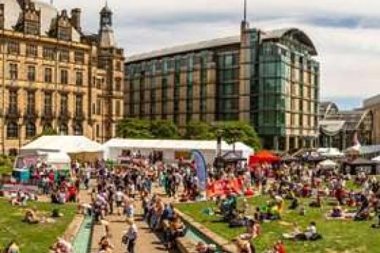 A packed Peace Gardens enjoying Sheffield Food Festival on a sunny day as people lay on the grass