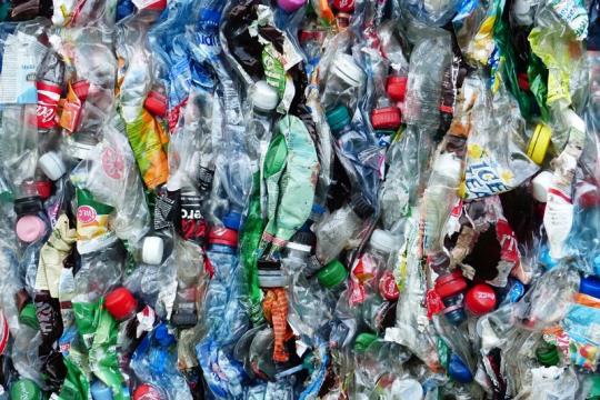 Plastic bottles crushed up and ready for recycling lie tightly packed together