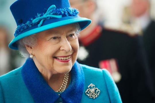 A smiling Queen Elizabeth the second wearing a blue hat and coat