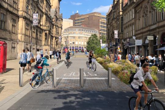 An artist impression of the pedestrianised Surrey Street with the Town Hall on the left, businesses on the right and people either walking or cycling along the middle of the picture