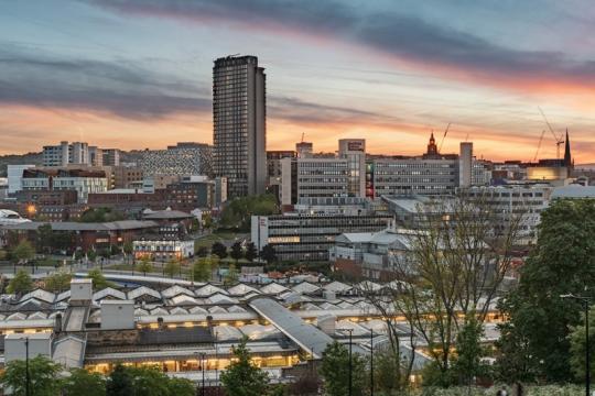 Sheffield's skyline with lit up buildings and an orange and blue sky