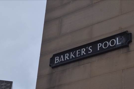 Sign saying Barker's Pool on a beige brick building with the grey sky in the background