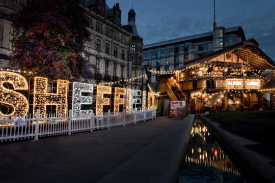 The word Sheffield is made up of giant letters covered in lights standing in front of the Town Hall with the Alpine bar building on the right hand side