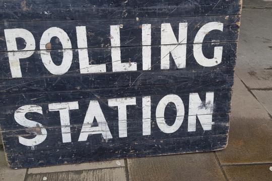 A blackboard sign with Polling Station written in white capital letters is propped up on the steps of Sheffield Town Hall