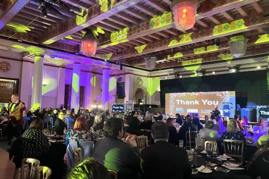 People watching the awards ceremony screen with lights on the colourful city hall ballroom ceiling