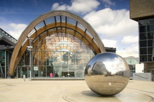 The outside of the Winter Garden with a large, shiny ball in front of it and blue skies 